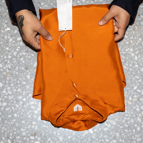 Hands of a man touching an orange folded shirt