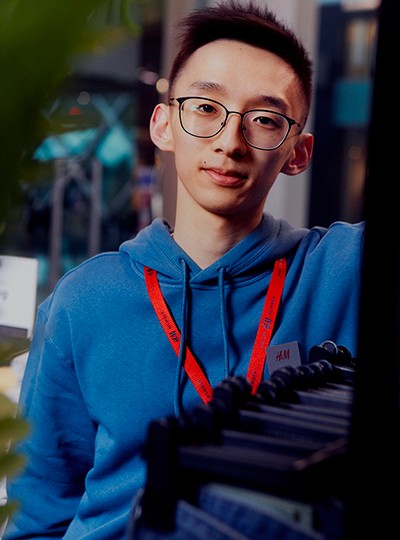 Male store employee looking into the camera. Standing near a rail of clothes.