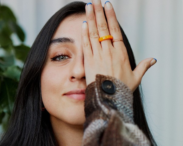 Een vrouw kijkt naar de camera en bedekt een oog met haar hand.