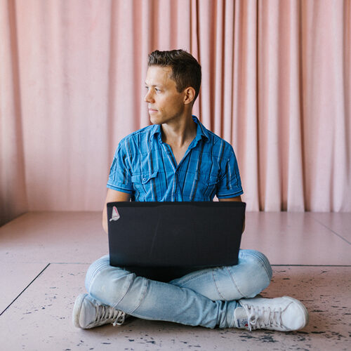 Man zittend op de vloer met een laptop