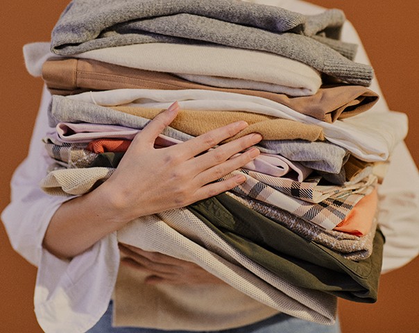 Vue de mains tenant une pile de vêtements pliés.