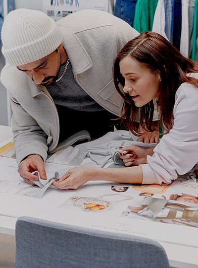 Un collaborateur et une collaboratrice travaillant ensemble penchés sur une table à regarder des échantillons de tissu