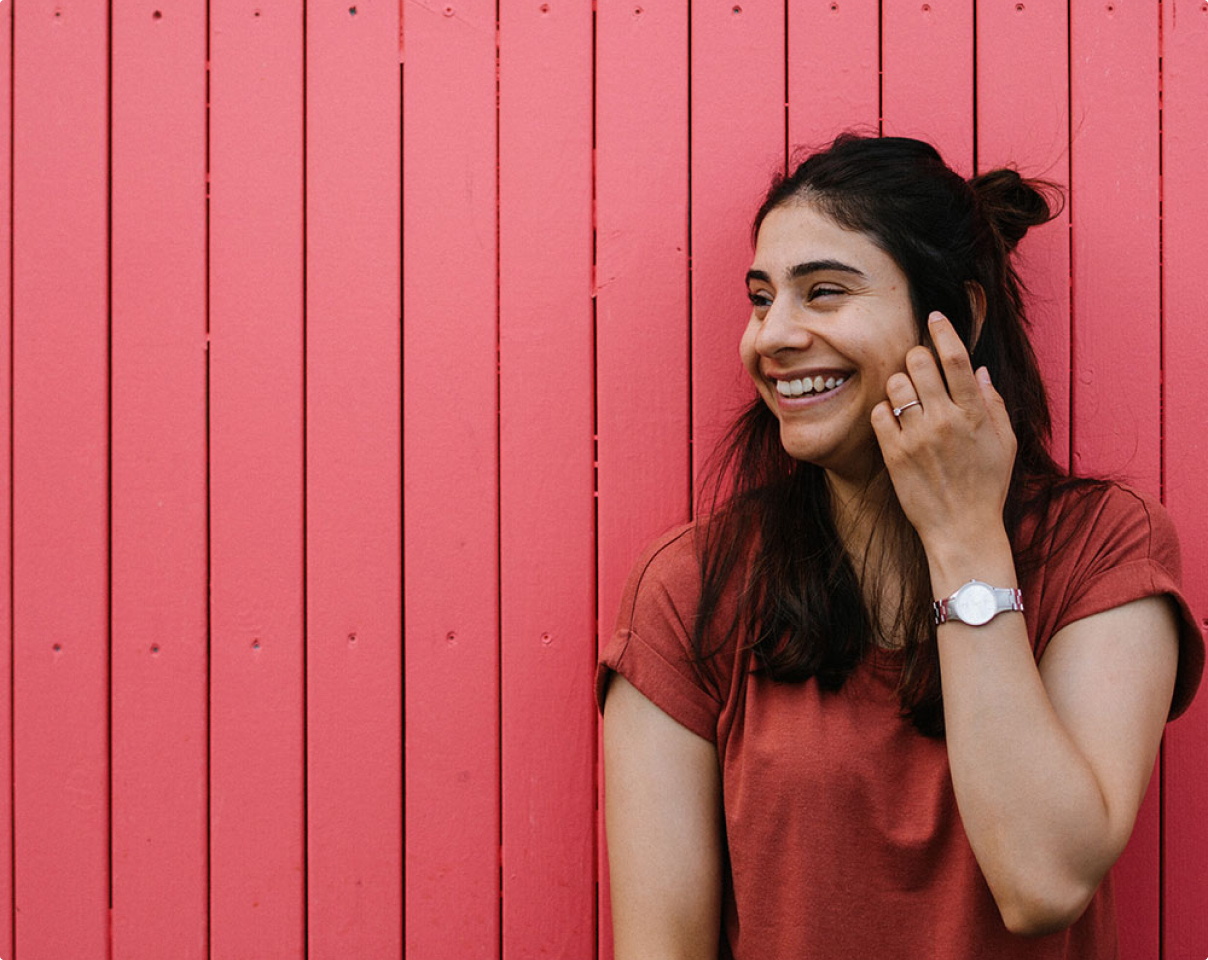 Uma jovem mulher a rir e a olhar para fora das câmaras.