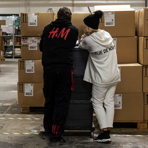 Two colleagues talking by a stack of cardboard boxes